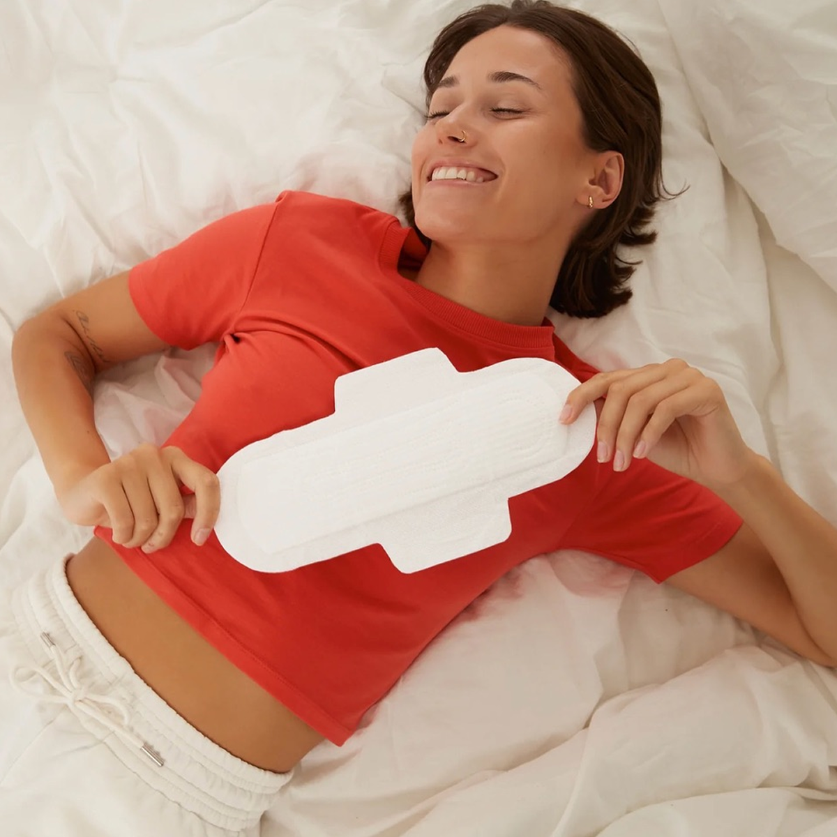 Smiling woman holding an Alea organic cotton pad